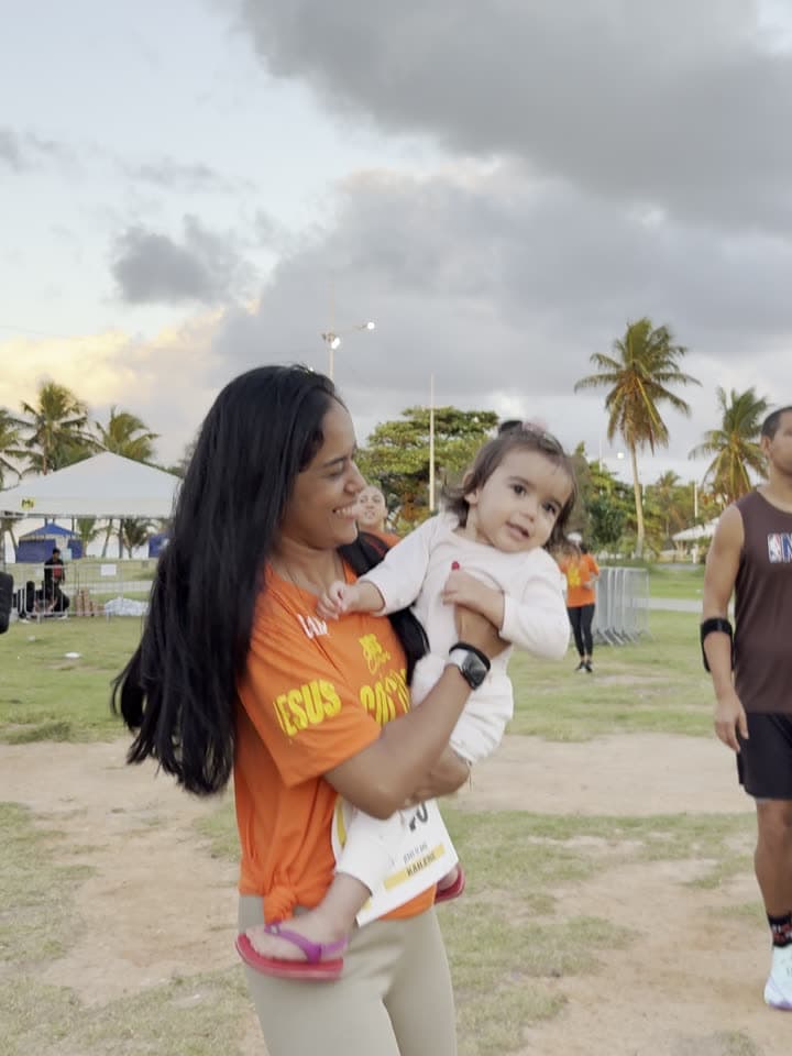 Mãe com a filha no colo, as duas com a camisa do evento
