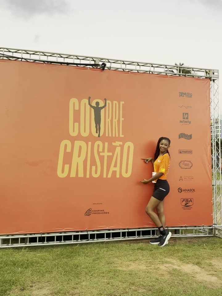 Corredora posando em frente ao painel do Corre Cristão